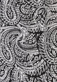 Tessuto in bianco e nero con intricate e vorticosi motivi paisley e floreali, caratterizzato da spessori di linea e dettagli variabili.