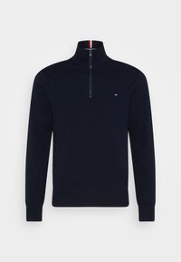 Pull quart-zip bleu marine en tissu doux, avec col et poignets côtelés. Petit logo en rouge, blanc et bleu sur la poitrine.