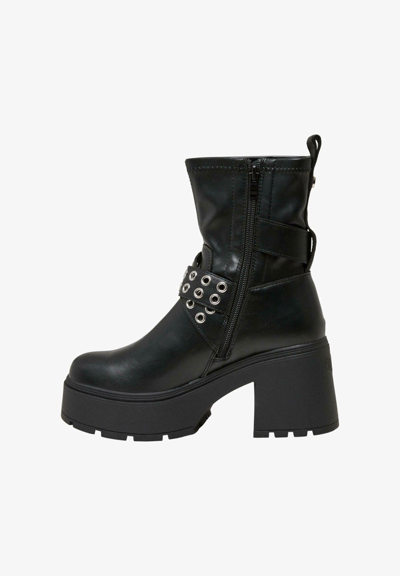 Botín negro hasta el tobillo con un tacón grueso, cierre con cremallera y una correa decorativa con ojales metálicos. Material de cuero sintético liso.