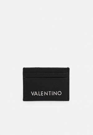 Crni teksturirani Valentino držač za kartice s dva utora za kartice i srebrnim logotipom na prednjoj strani na bijeloj podlozi.