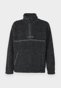Fleece pullover in dark gray with a high collar, quarter-zip, and contrasting green patterned accents along the chest and pockets.