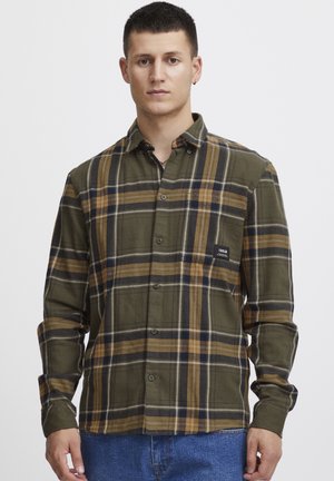 Camisa de franela abotonada en verde oliva y patrón de cuadros con acentos en amarillo y azul marino. Presenta un bolsillo en el pecho y textura suave.