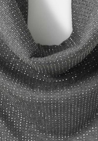 Grijze gebreide stof met fijne ribbelstructuur en subtiele zilveren versieringen, vormgegeven als een zachte, gestructureerde kraag. Gladde oppervlakte met een subtiele glans.