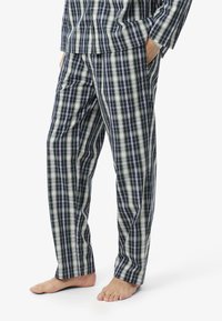 Pigiami a quadri in cotone nei colori blu navy, verde e bianco. Presentano una vestibilità ampia con vita elastica e tasche laterali. Texture morbida e leggera.