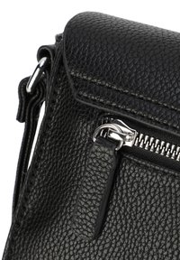 Schwarze, strukturiertes Lederhandtasche mit einem Reißverschluss, ausgestattet mit einem Klappenverschluss und silbernen Hardware-Akzenten. Die Form ist rechteckig mit einem Schultergurt.