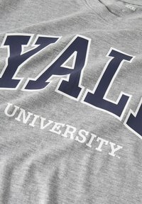 Grå bomulds t-shirt med stort marineblåt "YALE" tryk og "UNIVERSITY" i hvidt, med en rund halsåbning og blød tekstur.