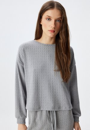 Suéter gris hecho de una tela de punto texturizada con un patrón de canalé, cuello redondo y mangas largas, que presenta un ajuste holgado y un largo cortado.