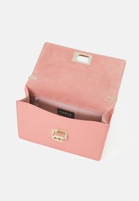 Borsa a mano in pelle rosa con chiusura dorata, aperta che mostra l'interno in suede e una tasca con zip con etichetta del marchio Furla.