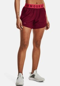 Bordeauxrote Sportshorts mit einem breiten pinken Bund, versehen mit einem Logo am Saum. Hergestellt aus einem leichten, atmungsaktiven Stoff.