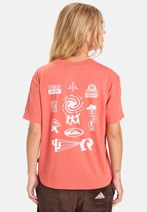 T-shirt corail à manches courtes avec des impressions graphiques blanches, comprenant des symboles et du texte, conçu avec une coupe décontractée et un col rond.