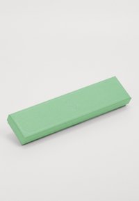 Roheline ristkülikuline paberpakend tekstureeritud pinnaga, veidi kitsenevate otstega ja reljeefsete detailidega, mõõtmetega umbes 15 cm x 3 cm.
