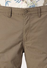 Khaki szorty wykonane z lekkiej bawełny, z zapięciem na guzik, szlufkami na pasek oraz widocznymi detalami przeszycia.