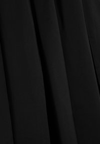 Zwart geplooid stof, lichtgewicht met een gladde textuur. Het materiaal is uniform van kleur, waardoor een vloeiende vorm ontstaat met duidelijke plooien.