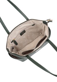 Sac à main en cuir vert avec une fermeture éclair et deux longues poignées. L'intérieur est doublé d'un tissu beige avec un motif imprimé subtil et une poche zippée.