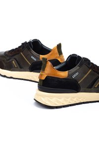 Zapatillas deportivas que presentan una combinación de cuero negro, marrón y beige, paneles texturizados, suelas de goma resistentes y un contraste en la costura decorativa.