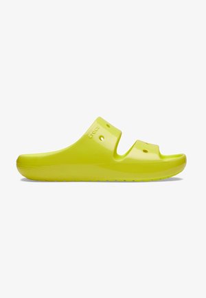 Sandalia tipo slip-on de color amarillo brillante con dos tiras y agujeros de ventilación, suela plana y la marca "Crocs" grabada en el lateral.