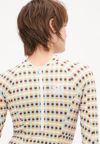 Long-sleeve rash guard featuring a multicolored checkerboard pattern in orange, blue, and brown, with a front zipper and logo detail.