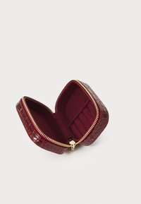 Pequeña caja de joyería burdeos con textura de cocodrilo, cremallera dorada y compartimentos acolchados para anillos en el interior.