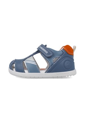 Sandalias sintéticas azules con recortes, correa ajustable, suela blanca y acento naranja en el talón. Nombre de la marca mostrado de manera prominente.