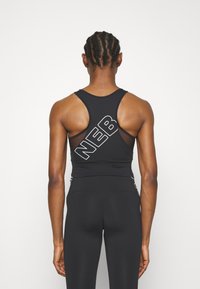 Camiseta deportiva negra sin mangas con diseño de espalda nadadora, que presenta un destacado logotipo blanco "NEB" en diagonal en la parte posterior. Textura suave, forma ajustada.