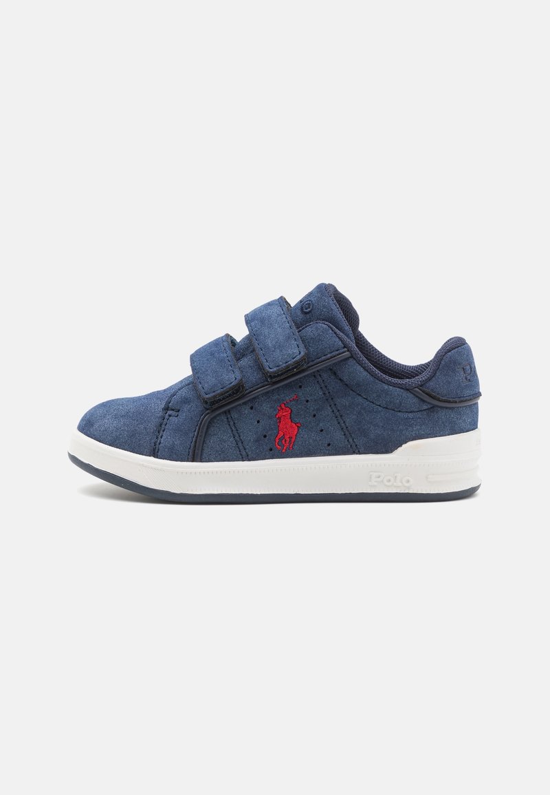 Baskets décontractées bleu marine avec deux bandes Velcro, semelle blanche et logo rouge Polo sur le côté, vues de l'extérieur.