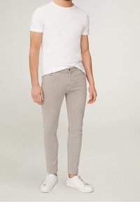 Camiseta blanca de cuello redondo combinada con jeans ajustados de color gris claro y zapatillas blancas, con un diseño minimalista y textura suave.