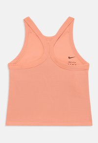 Persikinės spalvos sportinė topą su tekstūruota medžiaga, su lenkta nugarėle ir matoma Nike ženklinimu. Su Dri-FIT technologija.