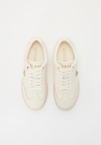 Vita lädersneakers med krämfärgade detaljer, rund tå och platta snören. Har varumärkesnamnet i guld på tungan och sidopanelen. Helt gummisula.