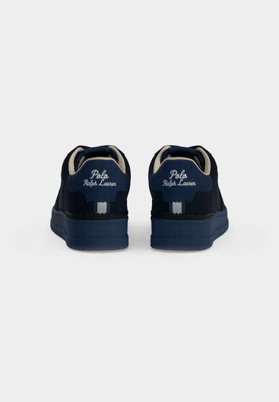 Ζευγάρι σκούρα μπλε αθλητικά παπούτσια Polo Ralph Lauren με λευκό λογότυπο και μπεζ εσωτερική επένδυση σε απλό φόντο, φωτογραφημένα από πίσω.