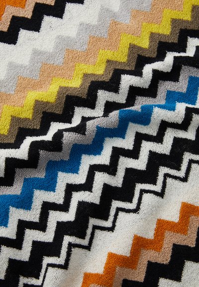 Flerfarget zigzag mønsterstoff, med svarte, blå, gule, grå og oransje nyanser, med en myk, teksturert overflate.