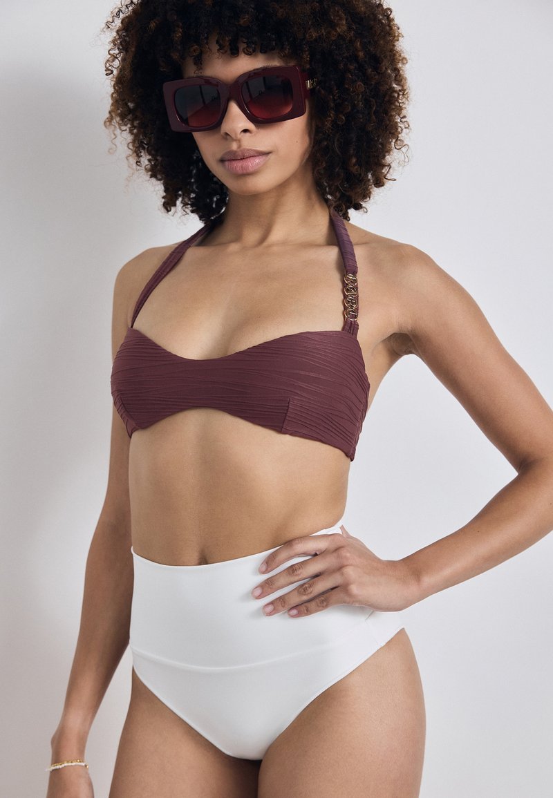 Bikini-Top in Kastanienbraun mit geripptem Textur und Halterneck; hochgeschnittene Bikinihose in Weiß mit glatter Oberfläche und minimaler Detailgestaltung.