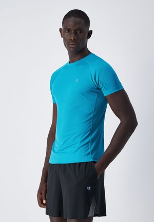Turquoise sportshirt met korte mouwen, voorzien van een gestructureerd patroon en een ronde halslijn, gecombineerd met zwarte shorts met zijsplitten en een logo.