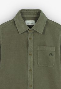 Camisa de pana verde oliva con cuello abotonado, que presenta un bolsillo en el pecho y un logo de calavera, acabada con botones marrones.