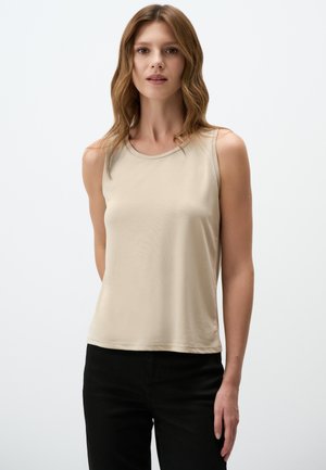 Haut sans manches beige en matériau doux, avec un col rond et une coupe décontractée. Assorti à un pantalon noir, design minimaliste.