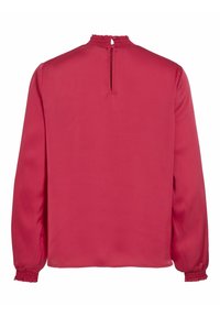 Blouse rouge à manches longues avec poignets et col smockés, dotée d'une ouverture en forme de goutte fermée par un petit bouton à l'arrière du col.