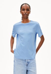 T-shirt bleu clair à manches courtes en coton doux, avec un col rond et une coupe décontractée, associé à un short en denim.