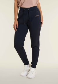 Pantaloni jogger navy in tessuto morbido, con cintura regolabile tramite cordino, design affusolato e logo dorato sulla coscia sinistra.
