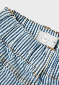 Črtaste denim kratke hlače z navpičnimi modrimi in belimi črtami, nabranim pasom in belim gumbom za zapiranje.