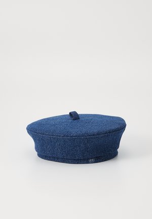 Sötétkék denim beret, lapos tetővel és kerek, formázott peremmel. Kis felső hurokkal rendelkezik a stílusos megjelenés érdekében. Simább textúra.