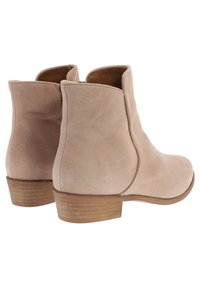 Beiga mockasin stövlar vid vristen med rundad tå, elastiska sidopaneler och en låg träklack. Slät yta med minimal sömnadsdetalj.