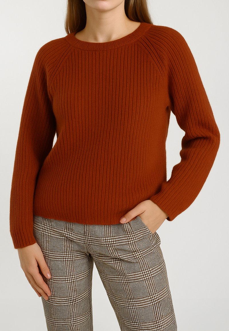 Maglione a coste in arancione bruciato con scollo rotondo classico, maniche lunghe e orlo aderente. Abbinato a pantaloni a quadri.