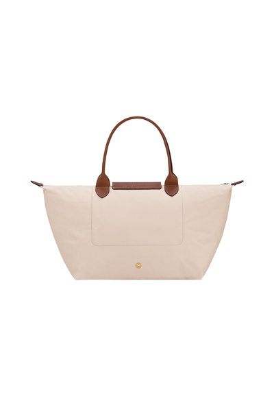 Beige large handbag with brown leather handles and a front pocket, featuring a small round gold button detail at the bottom center.