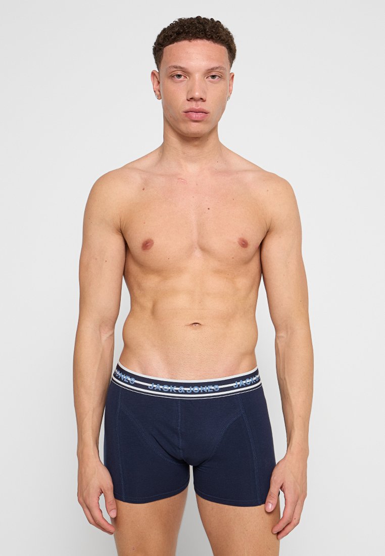Boxer shorts bleu marine avec une ceinture élastique blanche et bleue portant le nom de la marque "JACK & JONES." Le tissu semble doux et extensible.
