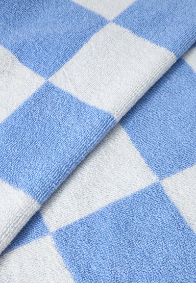 Μαλακό ύφασμα με μεγάλο μπλε και λευκό καρό σχέδιο, διπλωμένο ώστε να αναδειχθεί η υφή και τα χρώματα.