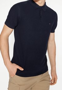 Námořnická polo košile s krátkým rukávem z texturované tkaniny, s žebrovaným límcem a zapínáním na tři knoflíky. Malé logo na hrudi.