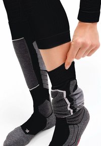 Czarne i szare skarpetki uciskowe z wzorem, z prążkowaną górną częścią, teksturowanymi dolnymi sekcjami oraz bezszwowym palcem. Ręcznie regulowany mankiet przy kostce.