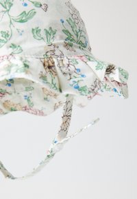 Gorro de sol para bebé con estampado floral, hecho de tela suave. Presenta un ala rizada, tirantes para la barbilla y cierre de botón. Los colores incluyen blanco, verde, rosa y azul.