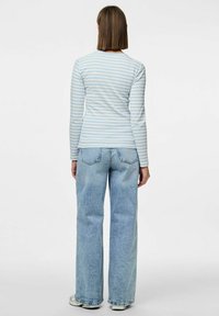 Långärmad topp med ljusblå och vita ränder, figurnära design, kombinerad med hög midja och löst sittande ljusblå jeans.