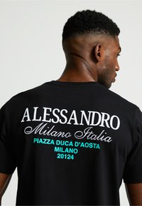 Camiseta negra de manga corta con texto en blanco y turquesa. El texto incluye "ALLESSANDRO," "Milano Italia," y detalles de ubicación.