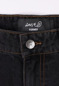 Jean en denim noir avec coutures orange. Comprend un bouton argenté avec un logo "F" et une étiquette noire avec les textes "DAVE" et "FORMER".